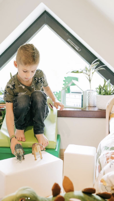 A boy playing with dinosaurs, sitting on his IGLU set