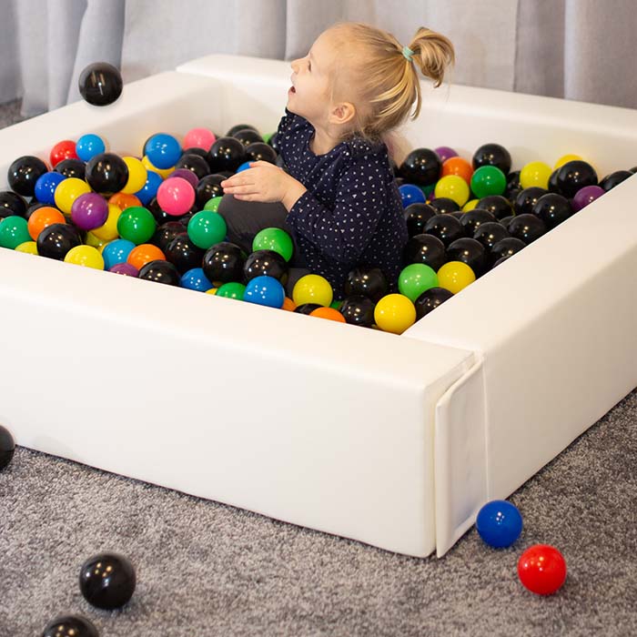 A girl playing in a white IGLU ball pit foam pool