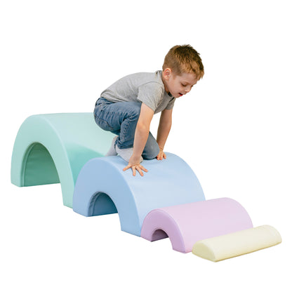 A boy climbs on soft play foam arches representing a rainbow in mint, blue, lavender, and cream pastel colors