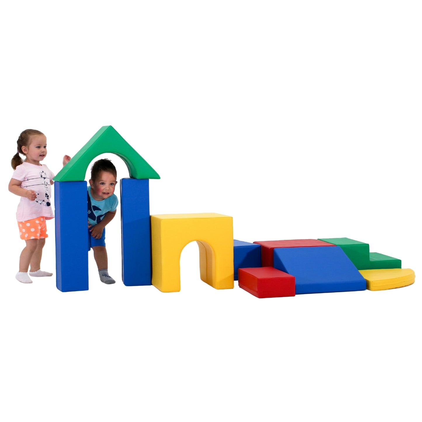 Toddlers standing by a colorful soft play fortress. Vibrant geometric shapes in various sizes form walls, towers, and arches