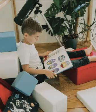 A boy reading a book, leaning against his IGLU set