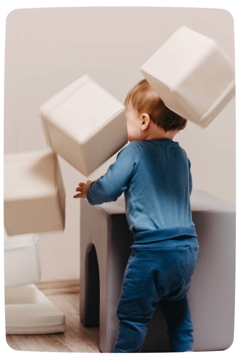 A baby boy throwing IGLU soft blocks