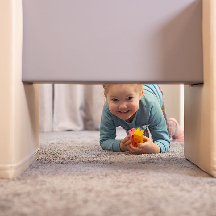 A little girl playing in an IGLU Soft Play - Soft Play Activity Set Balance Bridge, peeking out from under a chair.