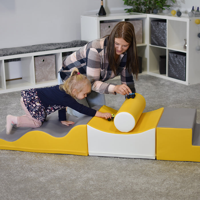 A woman and a child balancing on an IGLU Soft Play - Advanced Wave Walk soft play set.