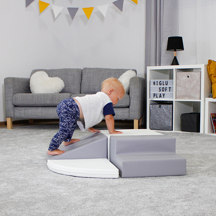 A baby is exploring an IGLU Soft Play Montessori-inspired adventure on a grey Soft Play Set - Corner Crawler play mat.